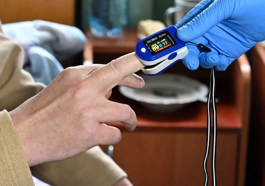 A medical worker checks the oxygen saturation on a patient at the intensive care unit the hospital, which treats patients with COVID-19 coronavirus in Kiev. - (Photo by Sergei SUPINSKY / AFP)